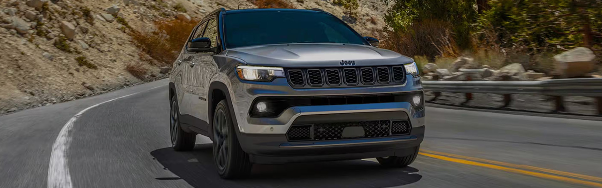 Jeep Compass SUV driving on mountain road.